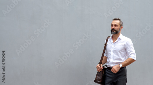 Portrait of Confidence Caucasian business man office worker carrying leather briefcase walking in city street to office district for working. Handsome beard guy entrepreneur enjoy outdoor city life.