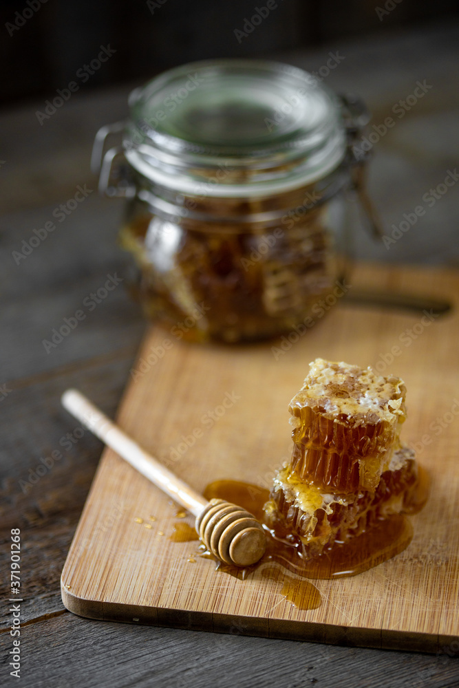 Pieces of fresh honeycomb with honey and glass jar on wooden background. Craft concept Pieces of fresh honeycomb with honey and glass jar on wooden background. Craft concept