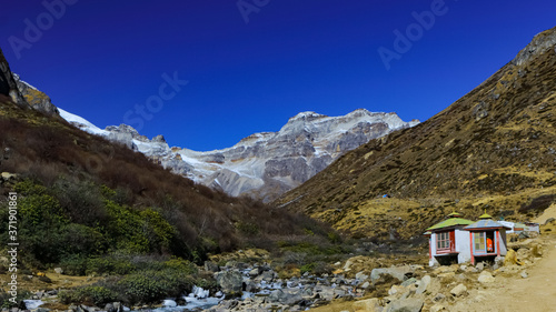 Selective focus image of a view of a valley with  small hut and snow clad peaks in the distant at North Sikkim in India