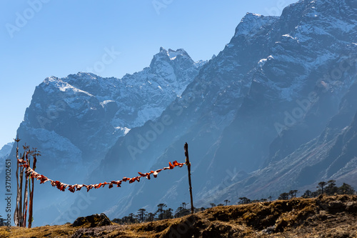 Selective focus image of Tibetan prayer flags blowing with the wind with high mountain ranges in the background back lit with sun at the valley of flowers in Sikkim India