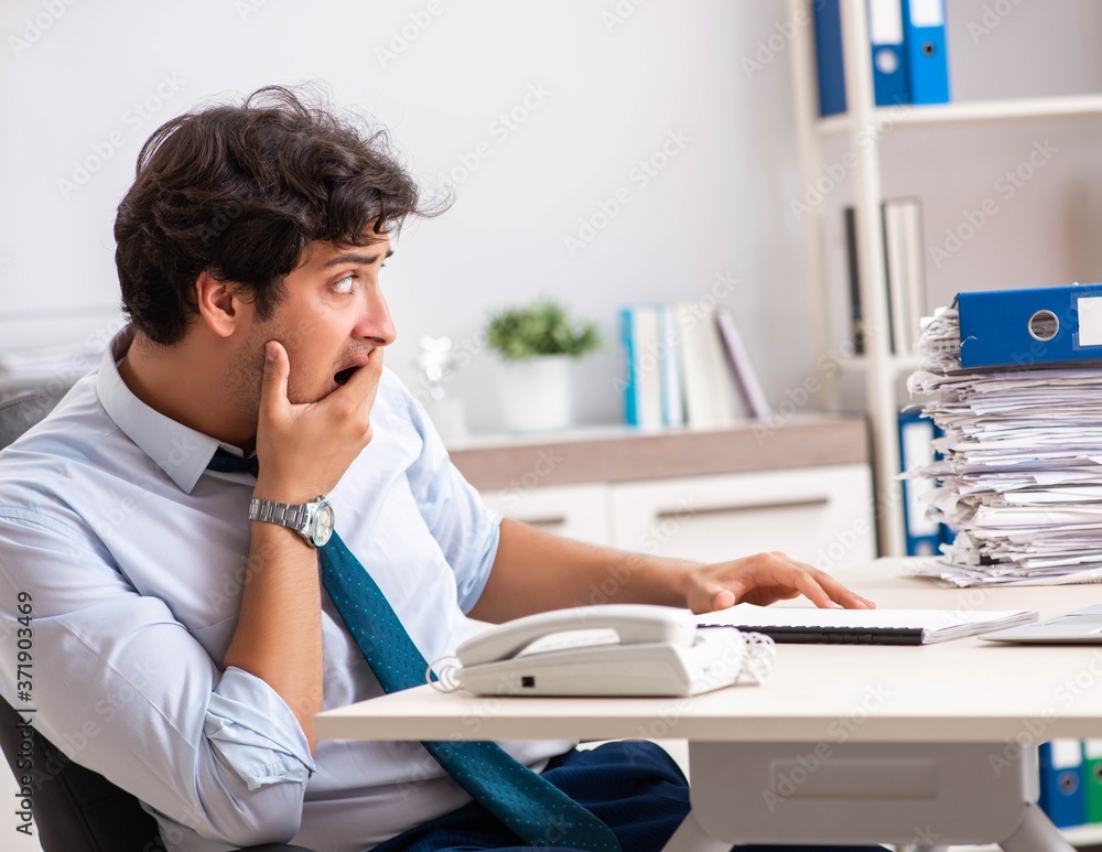 Overloaded busy employee with too much work and paperwork Overloaded busy employee with too much work and paperwork