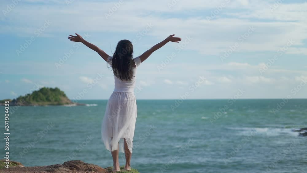 Slow motion clips,A beautiful woman wearing a white dress stands on the rocks by the sea, Koh Samed in Thailand. Slow motion clips,A beautiful woman wearing a white dress stands on the rocks by the sea, Koh Samed in Thailand.