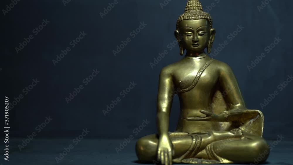golden meditating Idol face of buddha with a dark background and moving light golden meditating Idol face of buddha with a dark background and moving light
