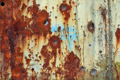 Old rusty metal background with bullet holes.