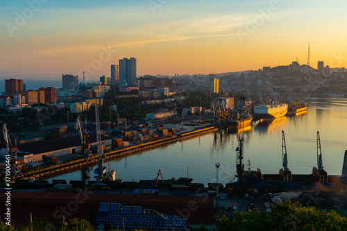 Summer, 2020 - Vladivostok, Russia - Dawn in Vladivostok. Aerial view of the Golden Horn Bay and the Commercial Sea Port. Cargo ships stand at the quay wall of the commercial port.