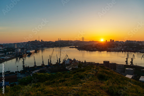 Summer, 2020 - Vladivostok, Russia - Dawn in Vladivostok. Aerial view of the Golden Horn Bay and the Commercial Sea Port. Cargo ships stand at the quay wall of the commercial port.