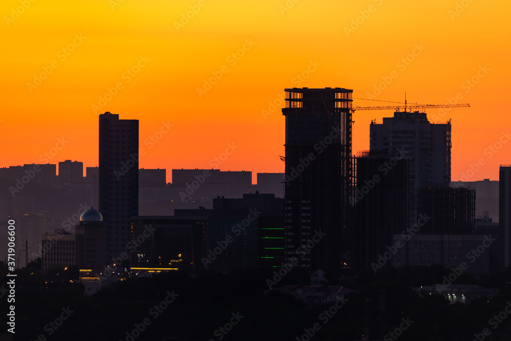 Vladivostok at dawn. Silhouettes of residential tall buildings against the backdrop of the rising sun.