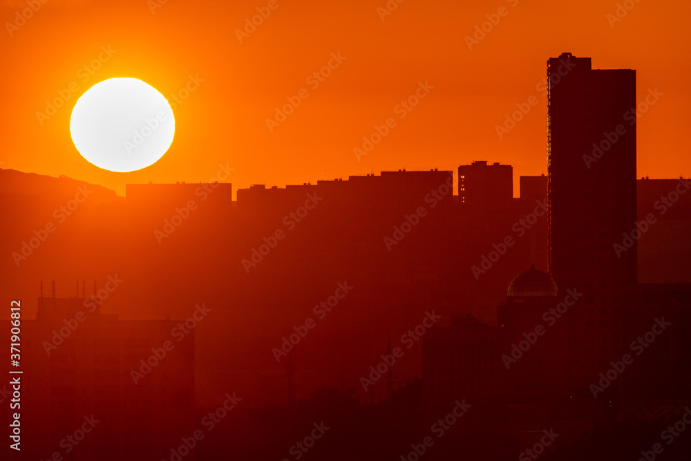 Vladivostok at dawn. Silhouettes of residential tall buildings against the backdrop of the rising sun.