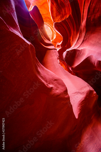 Penetrating light-stained sandstones stacked into flaky waves of fire in a narrow sandy labyrinth in Lower Antelope Canyon in Page Arizona