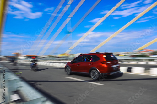 panning photo focus red or orange car on the road and bridge