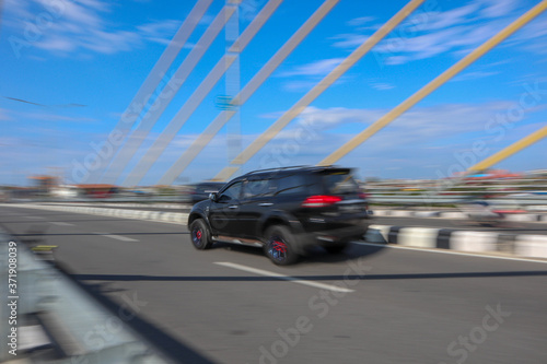 panning photo focus black car on the road and bridge