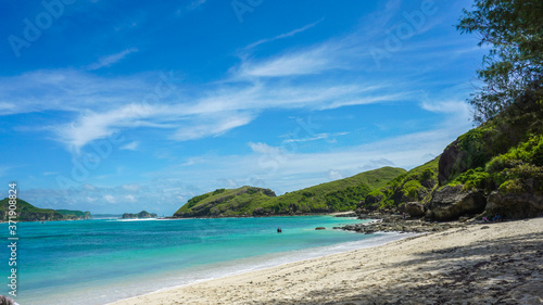 Sandy beach in an island in Bali with emerald colored ocean blue sky © Ingrid