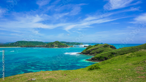 Green Hill at the Seashore in Bali with Emerald Colored Ocean, White Sand and Blue Sky