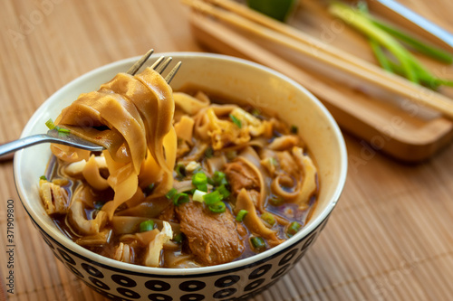 Картината върху платно In the foreground a wide yellow noodle on a fork