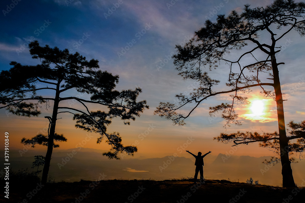 Silhouette of people standing in the air in Phu Kradueng National Park at sunrise in Loei Province, Thailand.
