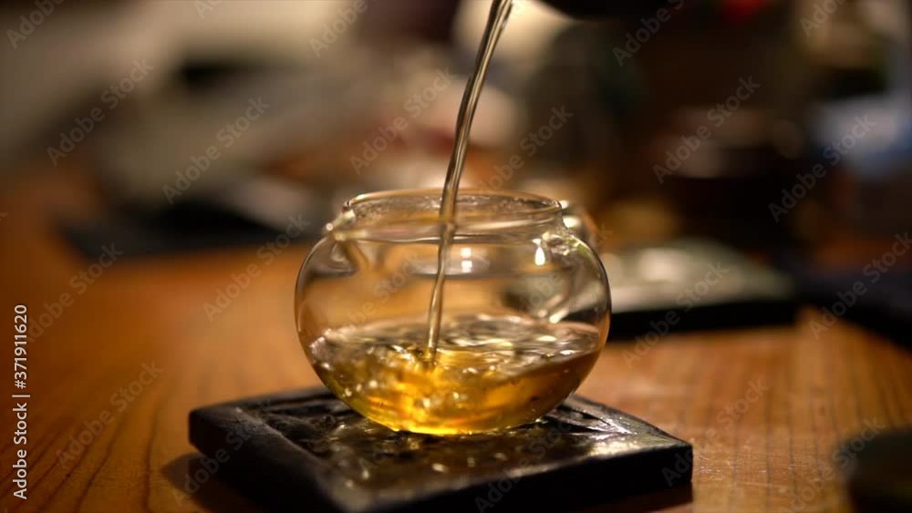 A man is drinking tea, pouring tea into a glass teapot A man is drinking tea, pouring tea into a glass teapot