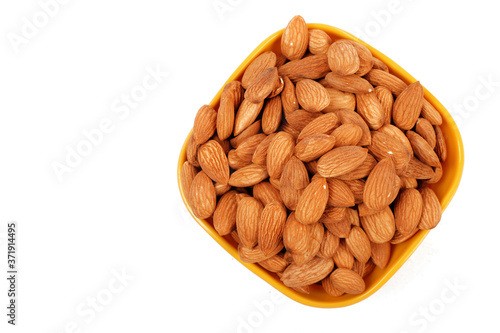 Group of almonds inside and outside bowl isolated on white.