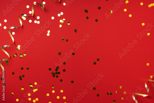 Golden confetti on red background with light bokehs. Happy new year celebration party. Greetings and congratulation concept. Festive backdrop with copy space for your design