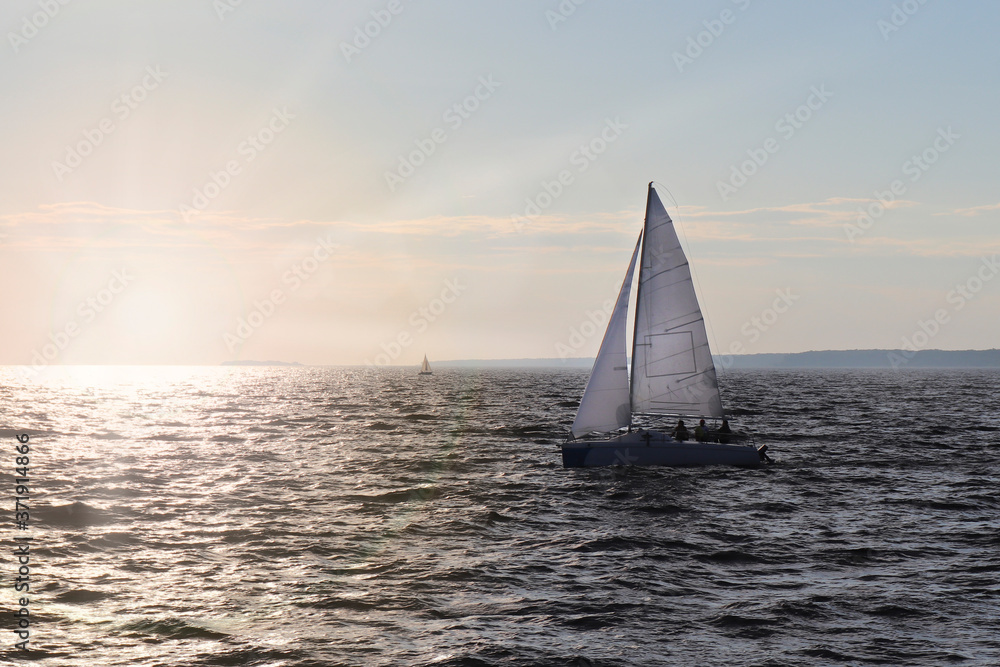 A sailing boat sails on the sea. Open sails. Active sport. Sailing on a yacht.
