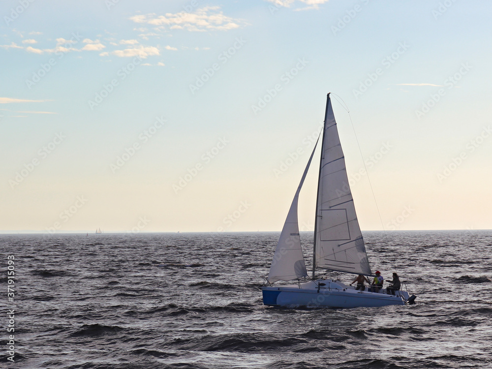 A sailing boat sails on the sea. Open sails. Active sport. Sailing on a yacht.