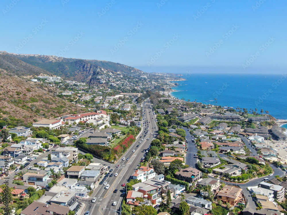 Aerial view of main road crossing Laguna Beach coastline town with houses on the hills and pacific ocean, Southern California Coastline, USA