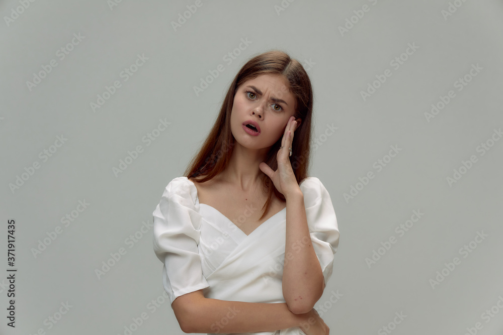 Surprised woman with open mouth holds hand near face white dress cropped Surprised woman with open mouth holds hand near face white dress cropped