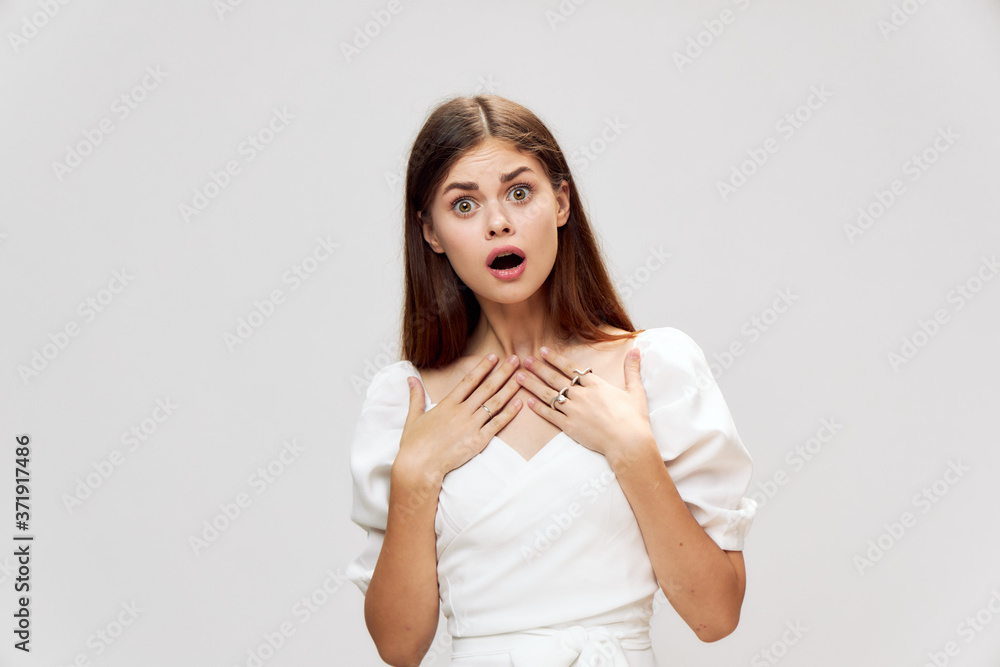 Surprised brunette with open mouth Wide open eyes in white dress cropped view Surprised brunette with open mouth Wide open eyes in white dress cropped view