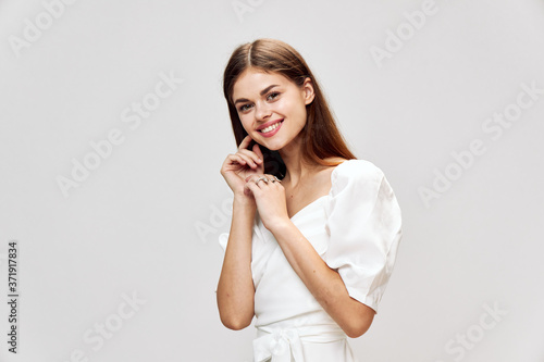 Smiling woman with long hair white dress hands near face 