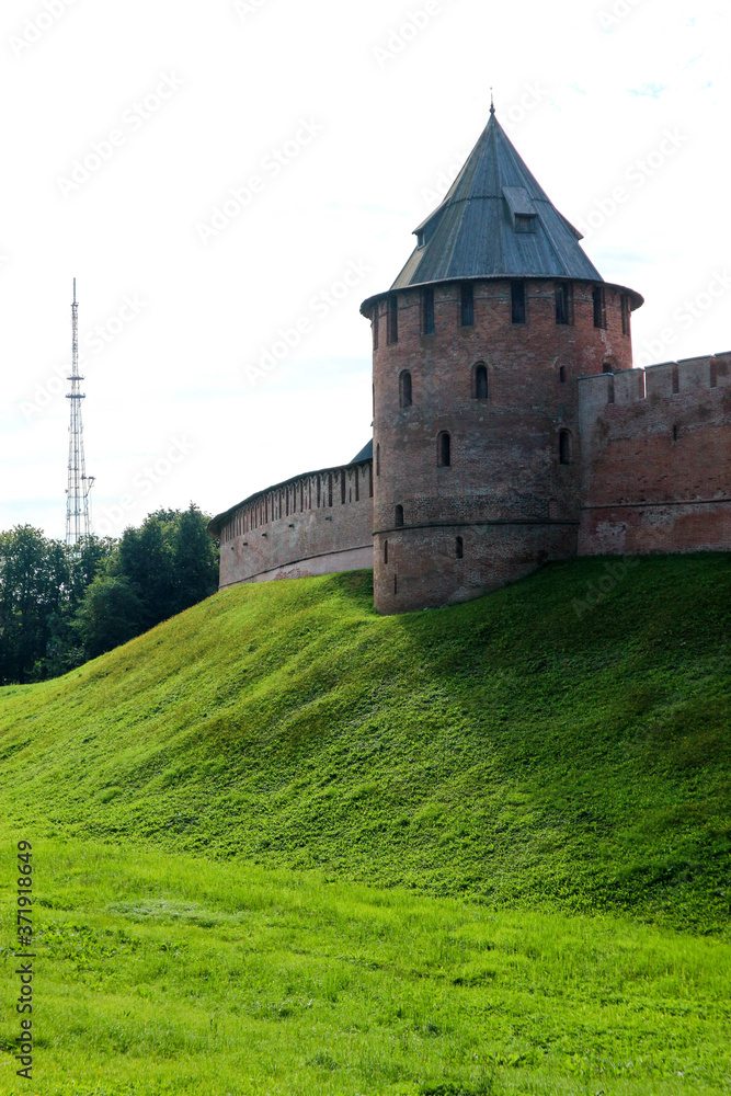 View to Metropolitan tower and wall of the Velikiy (Great) Novgorod citadel (kremlin, detinets) in Russia under blue summer sky in the morning View to Metropolitan tower and wall of the Velikiy (Great) Novgorod citadel (kremlin, detinets) in Russia under blue summer sky in the morning