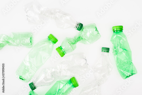 Top view of crumpled plastic bottles on white surface, ecology concept