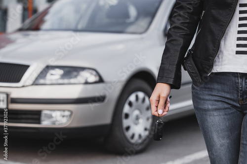 Car key in woman's hand against the new car background © Dmytro Titov