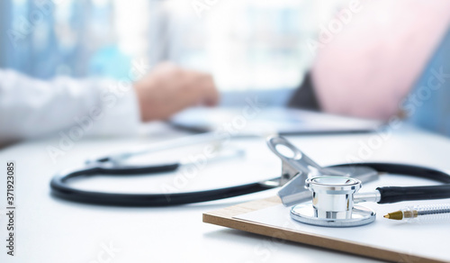 Online medicine concept. Stethoscope and clip board on the doctors workplace in the background, the doctor conducts an online patient consultation using laptop