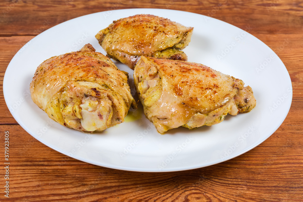 Fried chicken thighs on dish on rustic table close-up