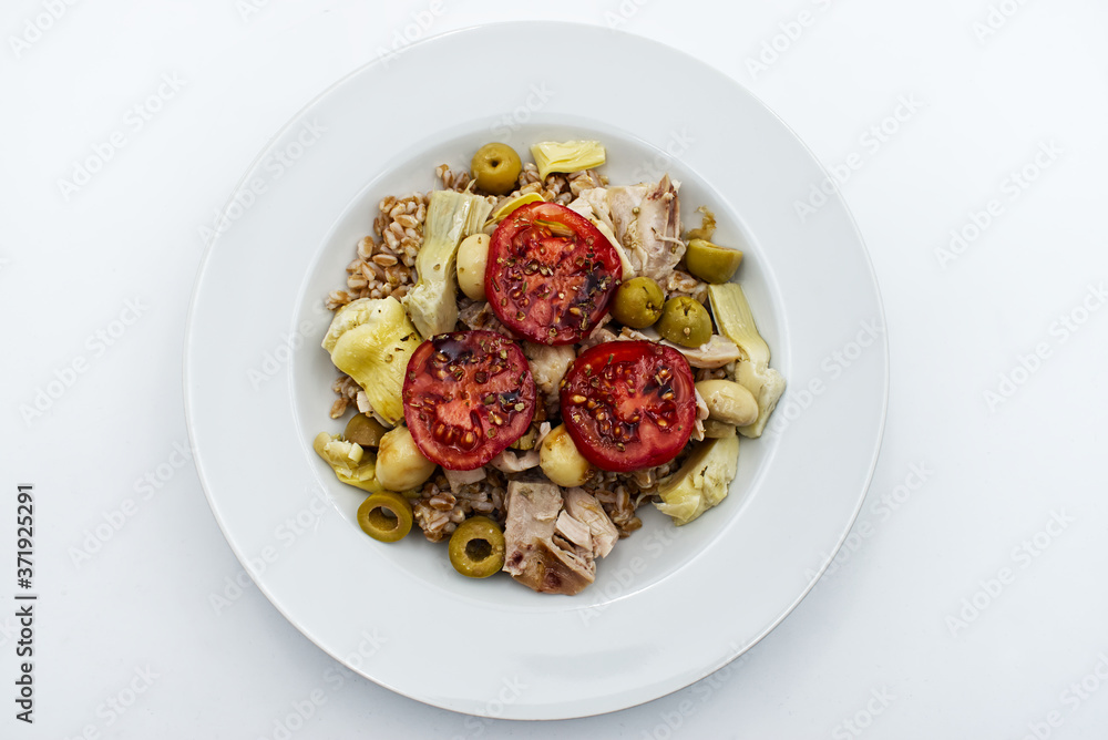 Fresh summer salad with: spelled, tomatoe, olive, mushroom and artichoke in white plate. Top view Fresh summer salad with: spelled, tomatoe, olive, mushroom and artichoke in white plate. Top view