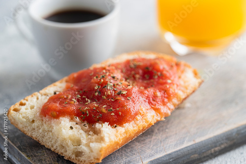 Pa amb tomaquet or tomaca (bread with tomato) classic snack in Catalan and Spanish cuisine, eaten for breakfast with cup of coffee and orange juice photo