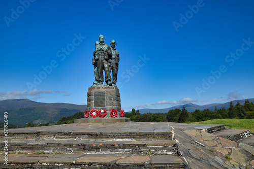 Public Commando Memorial near Spean Bridge, Scottish Highlands. Poppy wreaths at commandos feet. Summer with bright blue sky. Hills in background. photo