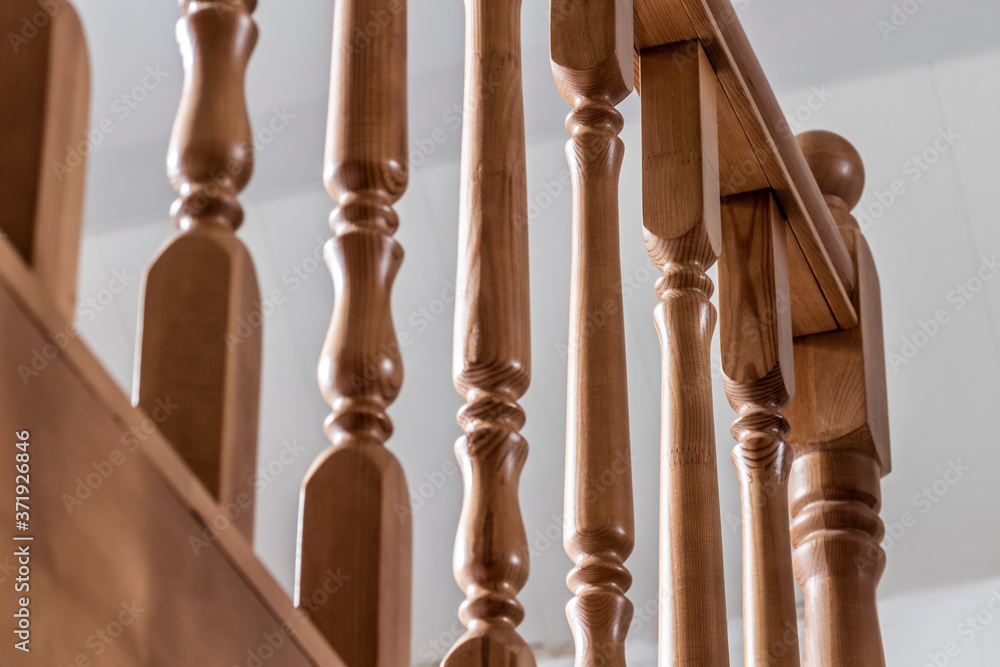 Fototapeta premium Element of a wooden interior staircase. Wooden baluster close-up.