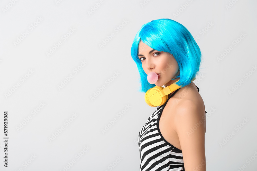Beautiful young woman in wig and with headphones on light background Beautiful young woman in wig and with headphones on light background
