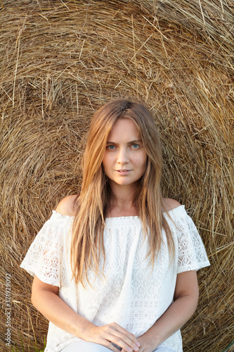 beautiful young woman against rolled hay stack