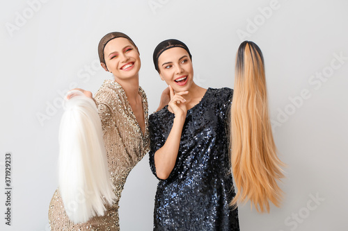 Beautiful young women with different wigs on light background photo