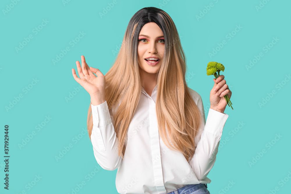 Beautiful young woman in wig and with flowers on color background Beautiful young woman in wig and with flowers on color background