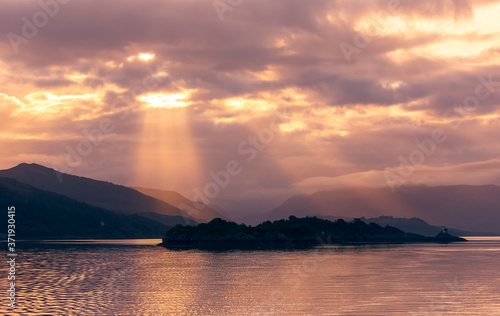 Sunrise in the Inner Hebrides  Scotland  with sunrays bursting through the clouds on the mountain range.  Concept  Tranquility.  Horizontal.  Space for copy.