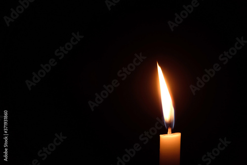 White candle flame closes upon a black background, Candle Burning in the Dark with lights glow, The burning candle's flame with light glow background a symbol of the Christian faith.