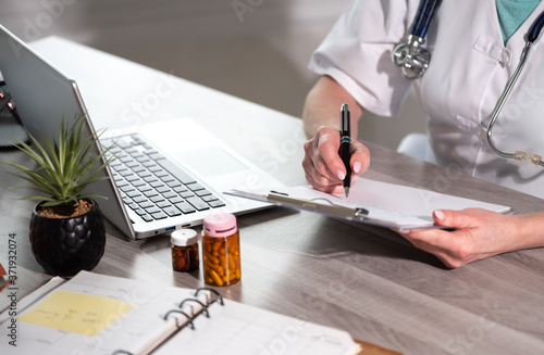 Female doctor taking notes on clipboard photo