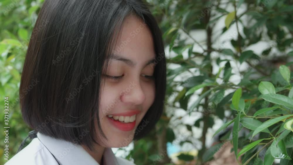 Slow motion of beautiful smiling Asian teen high school girl in white uniform relaxing in the park. Slow motion of beautiful smiling Asian teen high school girl in white uniform relaxing in the park.