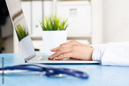 Close up of female doctor hands using laptop