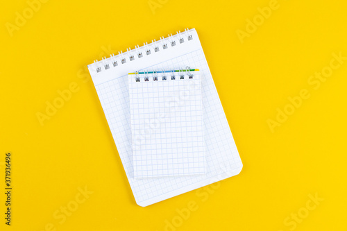Open notebook on bright yellow paper background. School accessory with copy space on color background. The concept of studying or planning. Flat lay.