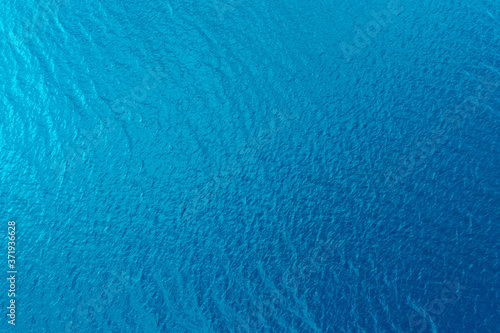 Aerial view of a crystal clear sea water texture. View from above Natural blue background. Blue water reflection. Blue ocean wave. Summer sea. Drone. Top view © Aleksei