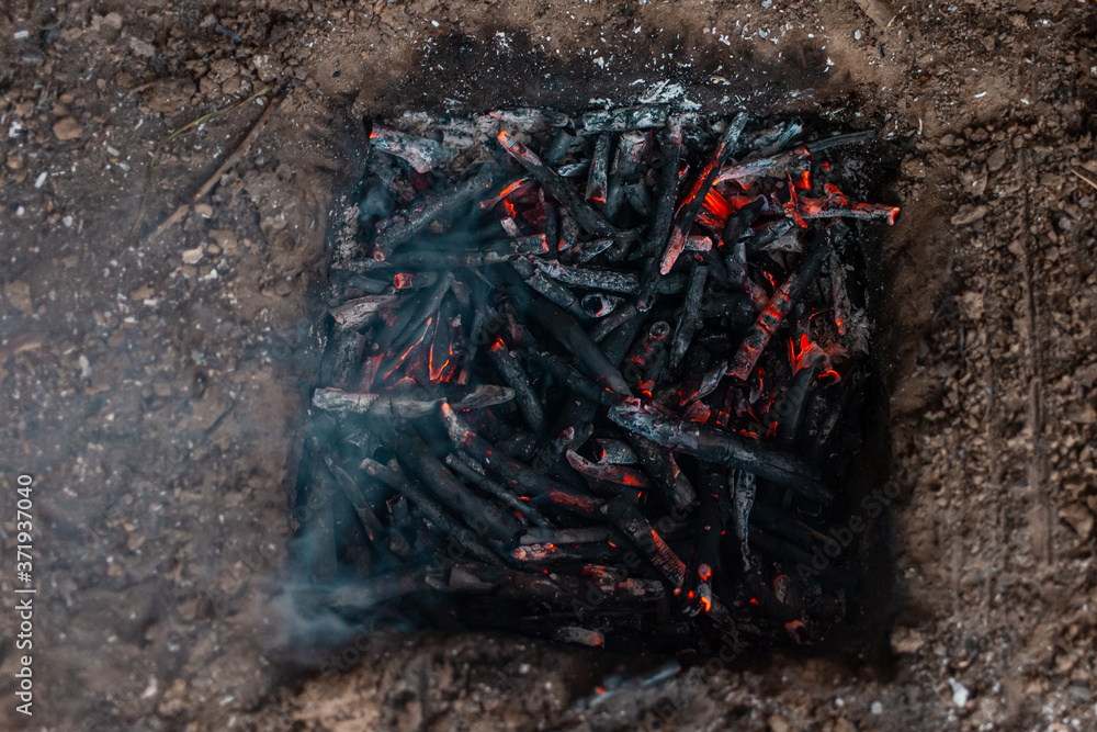 Coals from a campfire in a sand pit.