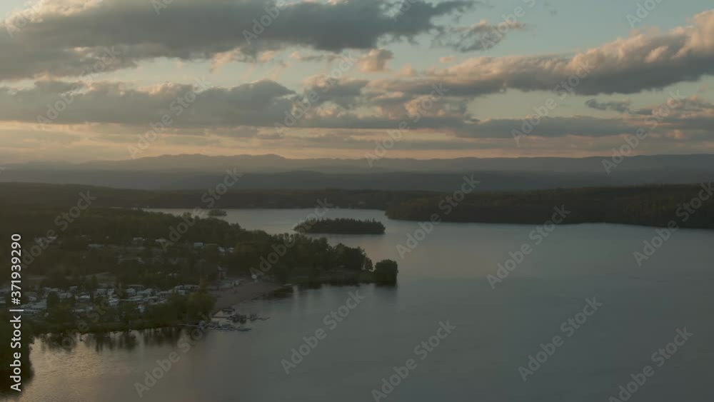Aerial view of calm Lake Otis and village in golden summer sunset light Aerial view of calm Lake Otis and village in golden summer sunset light